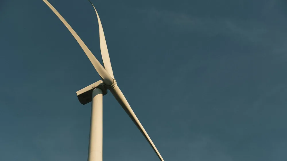 A wind turbine under a clear sky, symbolizing renewable energy and sustainability.