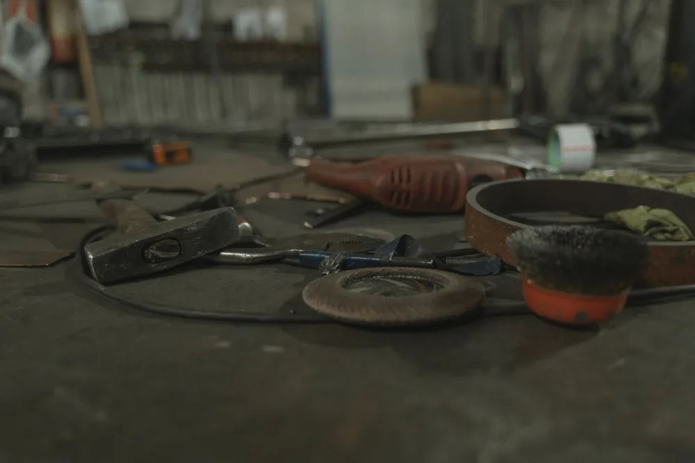A selection of various tools scattered on a workbench in an industrial setting.