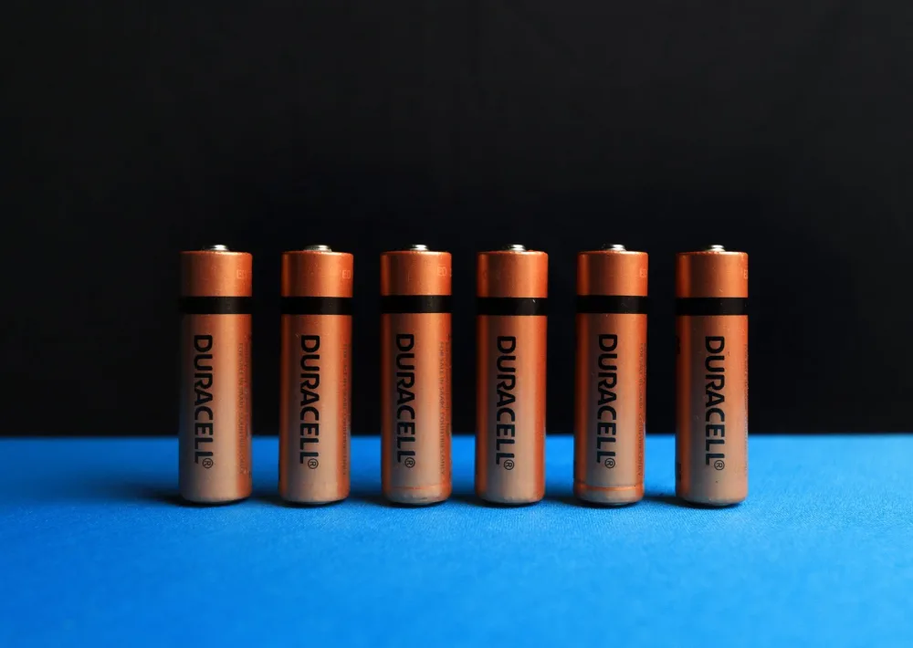 A lined up set of AA batteries with black and blue background.