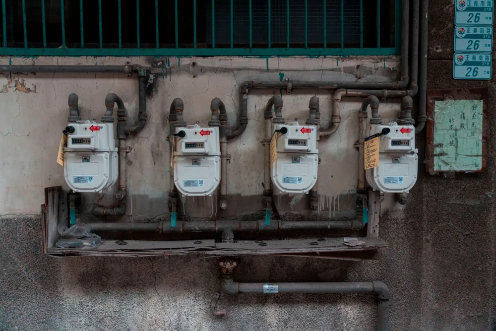 Four gas meters mounted on an exterior wall, showcasing urban utility infrastructure.