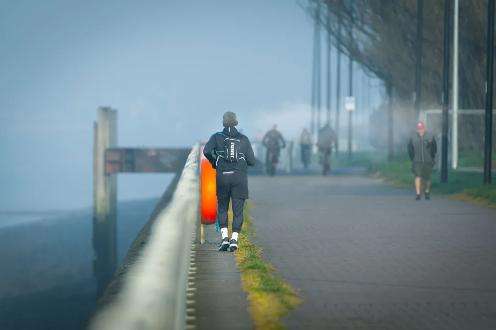 A lone jogger runs along a foggy coastal pathway, perfect for fitness and travel themes.