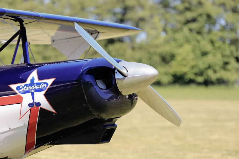 Vivid close-up of a vintage Staudacher aircraft propeller on a sunny day outdoors.