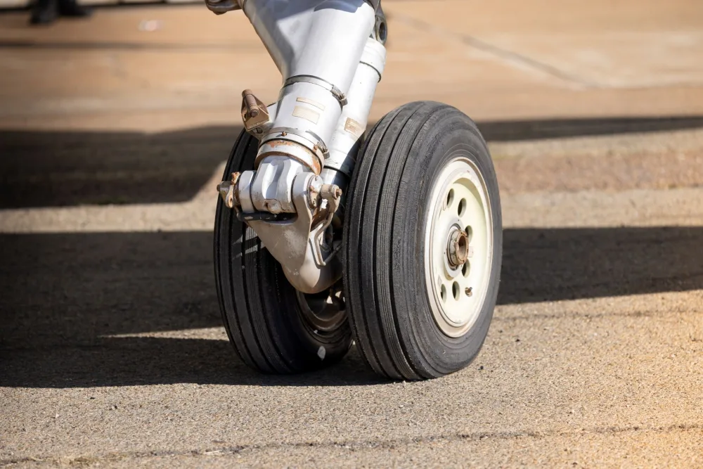 Detailed view of airplane landing gear on airport tarmac in daylight.