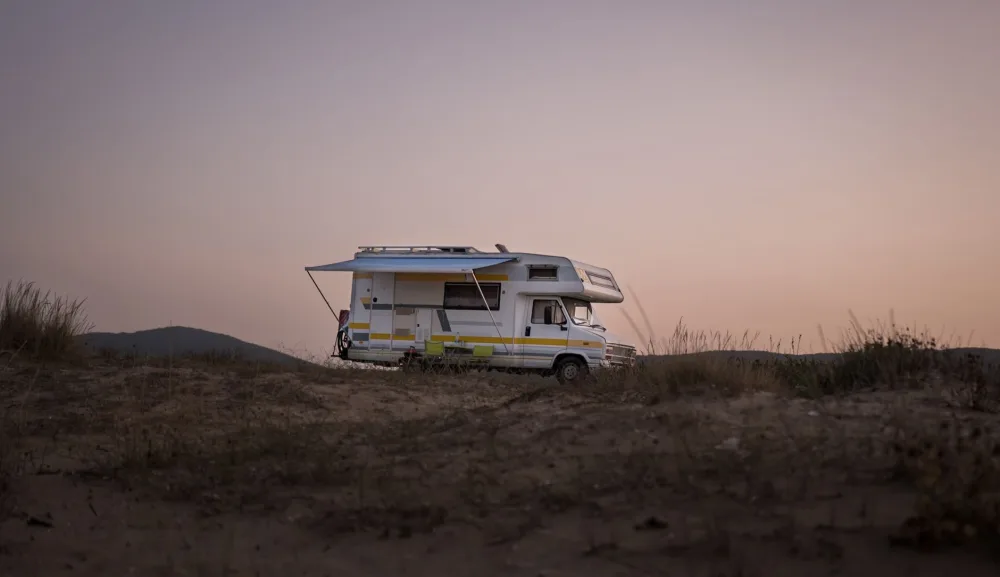 A serene view of an RV parked amidst nature during sunset, capturing a travel adventure.