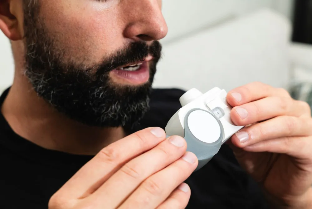 Close-up of a bearded man holding an inhaler, indicating respiratory care.