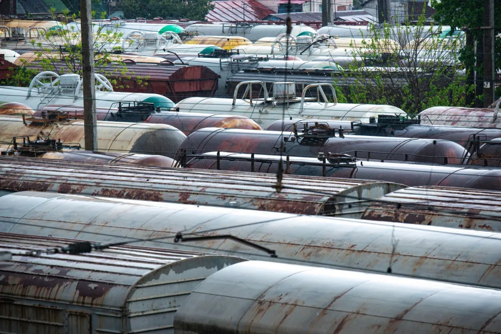 Aerial photograph showing an extensive array of weathered and rusted train cars in an outdoor rail yard.